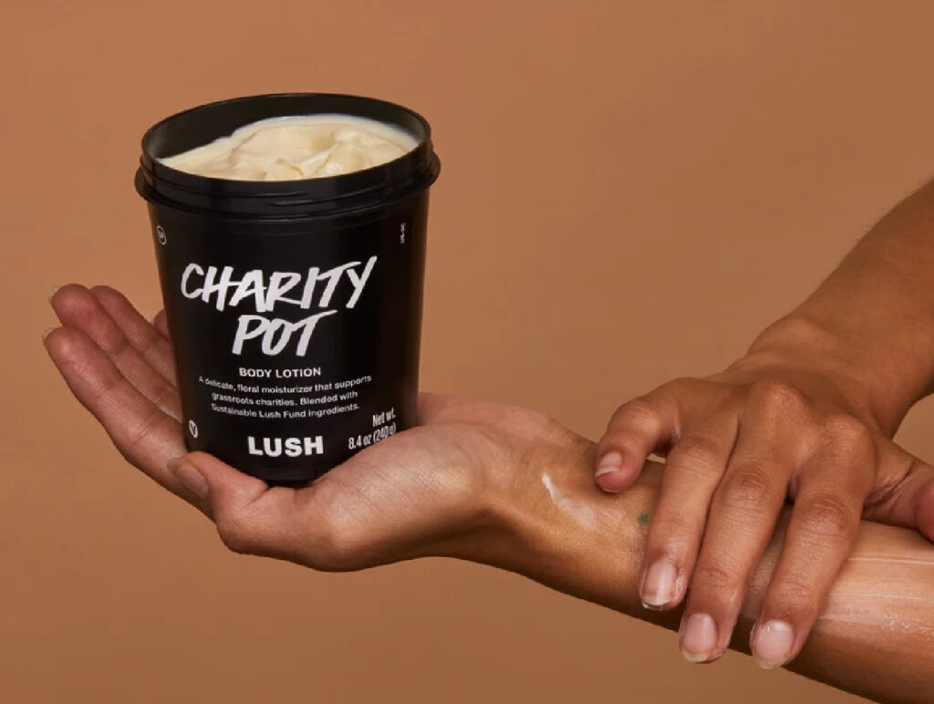 a hold handing a black pot saying 'charity pot' on a brown background