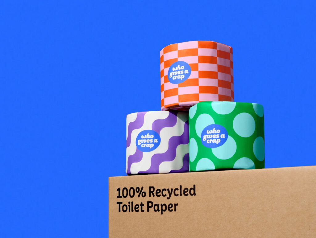 three wrapped toilet rolls sit on top of a box with a blue background